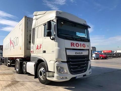 Camión DAF blanco con contenedor, estacionado sobre una superficie de hormigón en un día soleado. El camión luce el logotipo