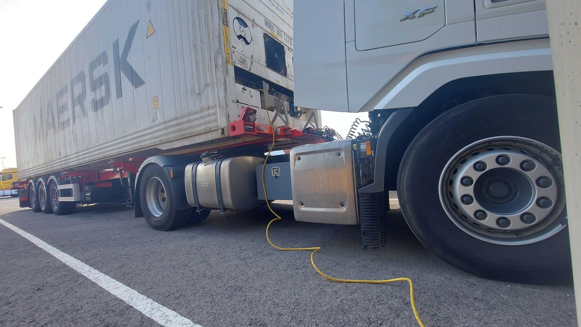 Camión semirremolque que transporta un contenedor de Maersk por una carretera, con marcas blancas.