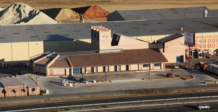 Una casa de ladrillo color canela con techo de tejas, entrada arqueada con dos columnas de piedra y palmeras a ambos lados.