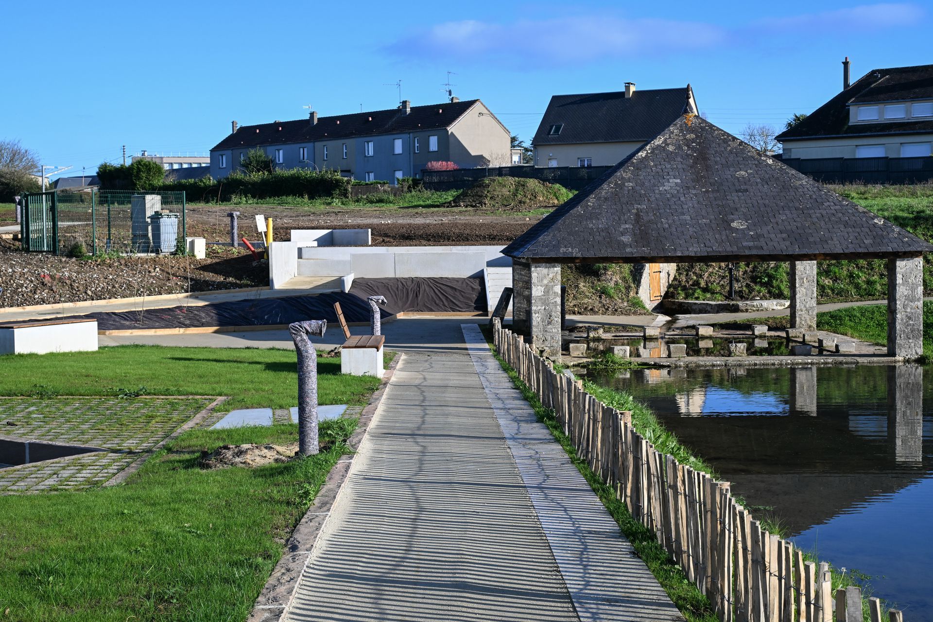 Belle allée avec palisse en bois sur le côté droit et lavoir au fond