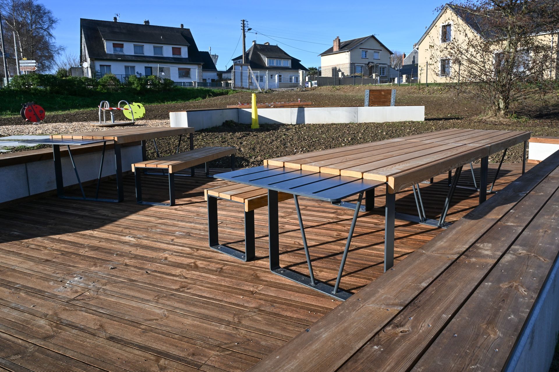 Table de pique-nique sur terrasse bois avec maison en arrière-plan
