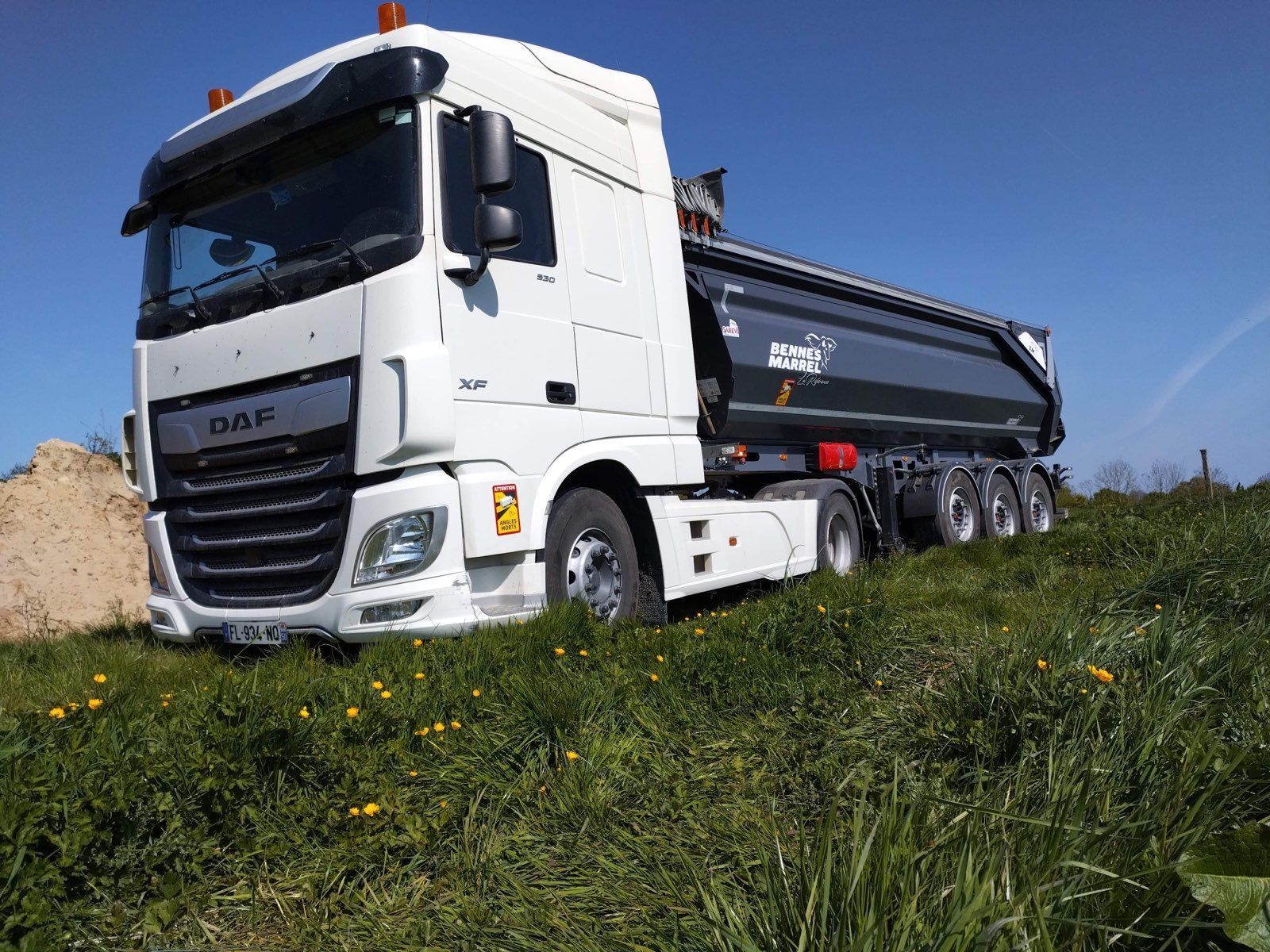 Camion blanc avec benne noire dans un pré