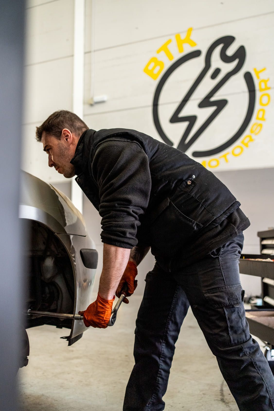 Un hombre está trabajando en un coche en un garaje.