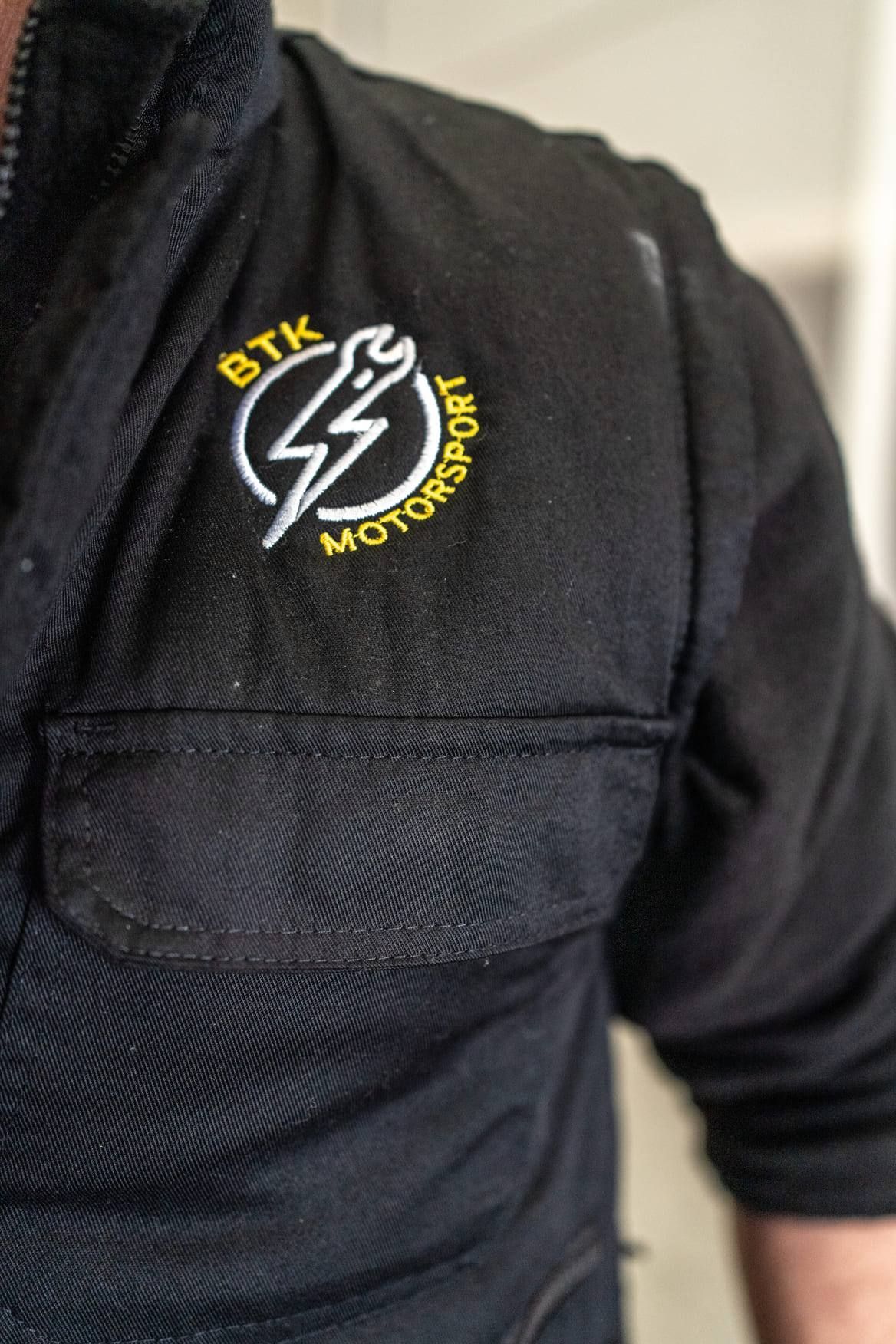 Un hombre lleva una camisa negra con un rayo bordado en ella.