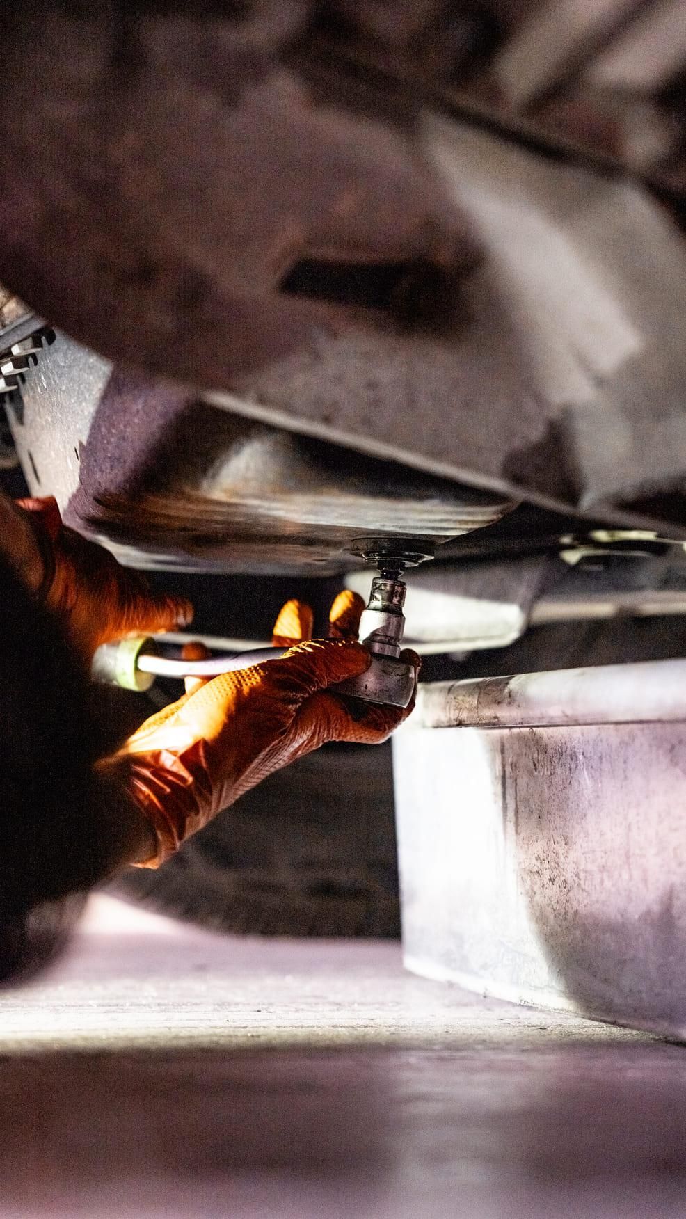 Una persona está trabajando en un coche con una llave inglesa.