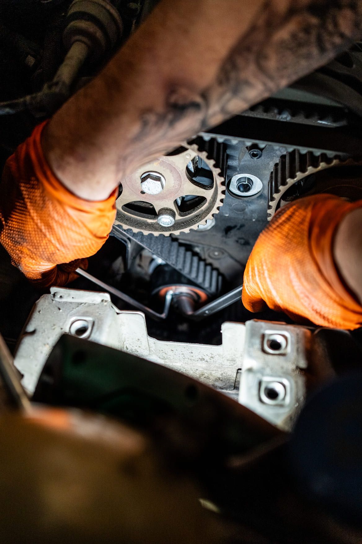 Una persona que lleva guantes naranjas está trabajando en el motor de un automóvil.