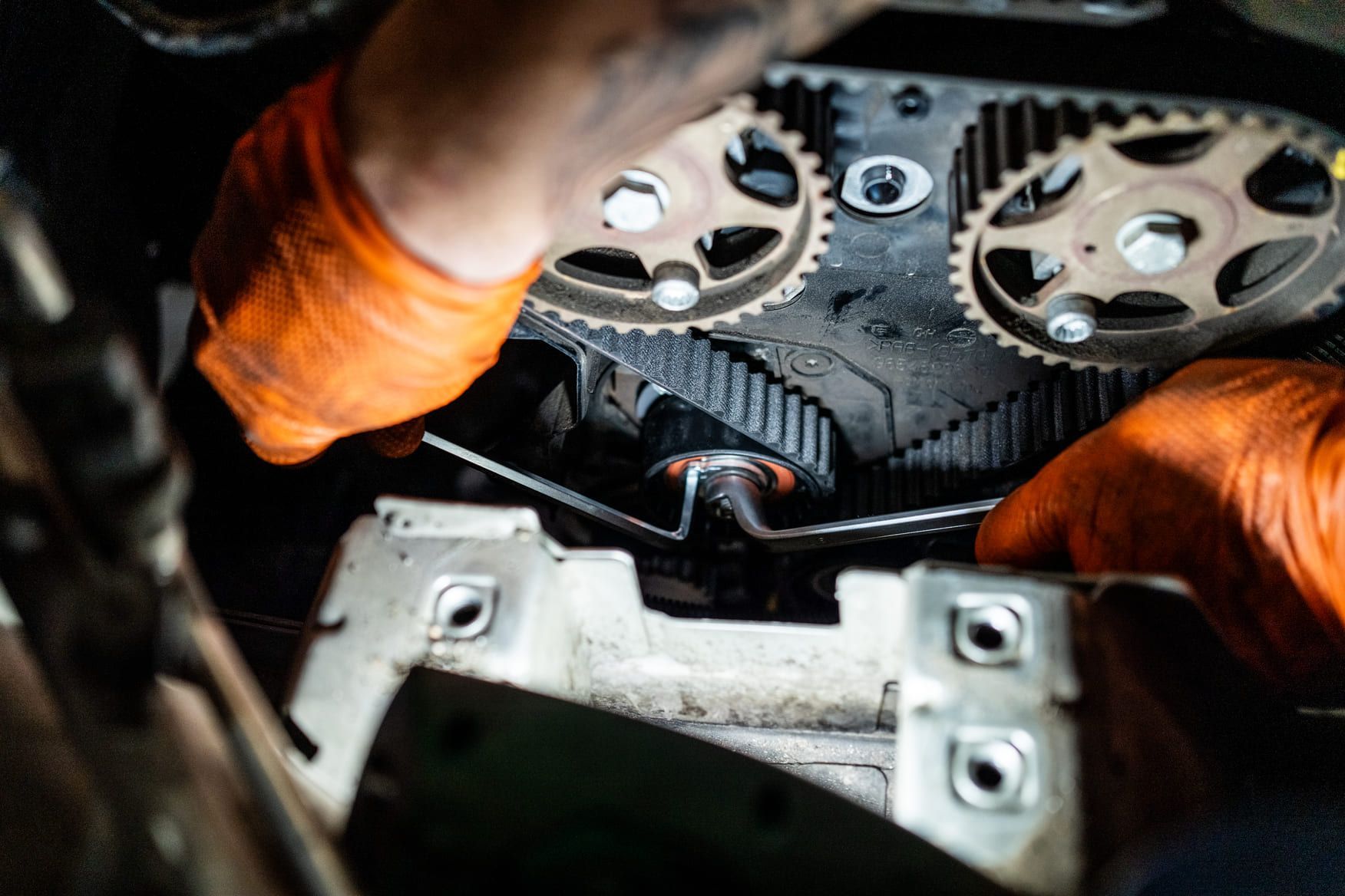 Una persona que lleva guantes naranjas está trabajando en el motor de un automóvil.