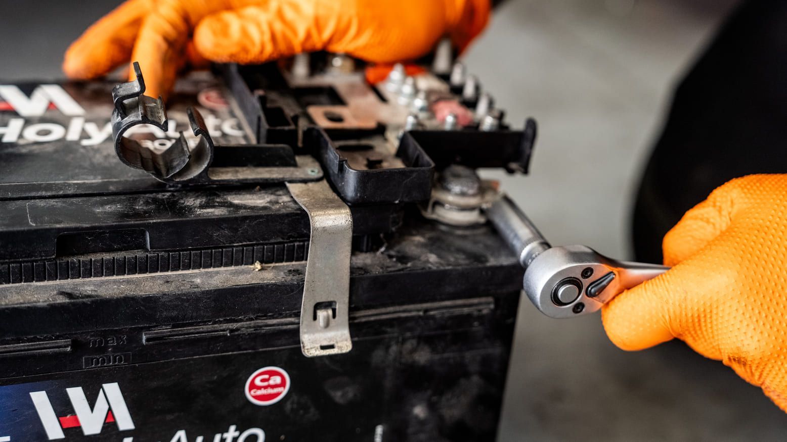 Una persona está trabajando en una batería de automóvil con una llave.