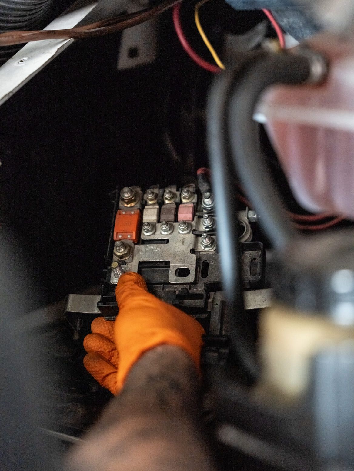 Una persona que lleva guantes naranjas está trabajando en una batería de automóvil.