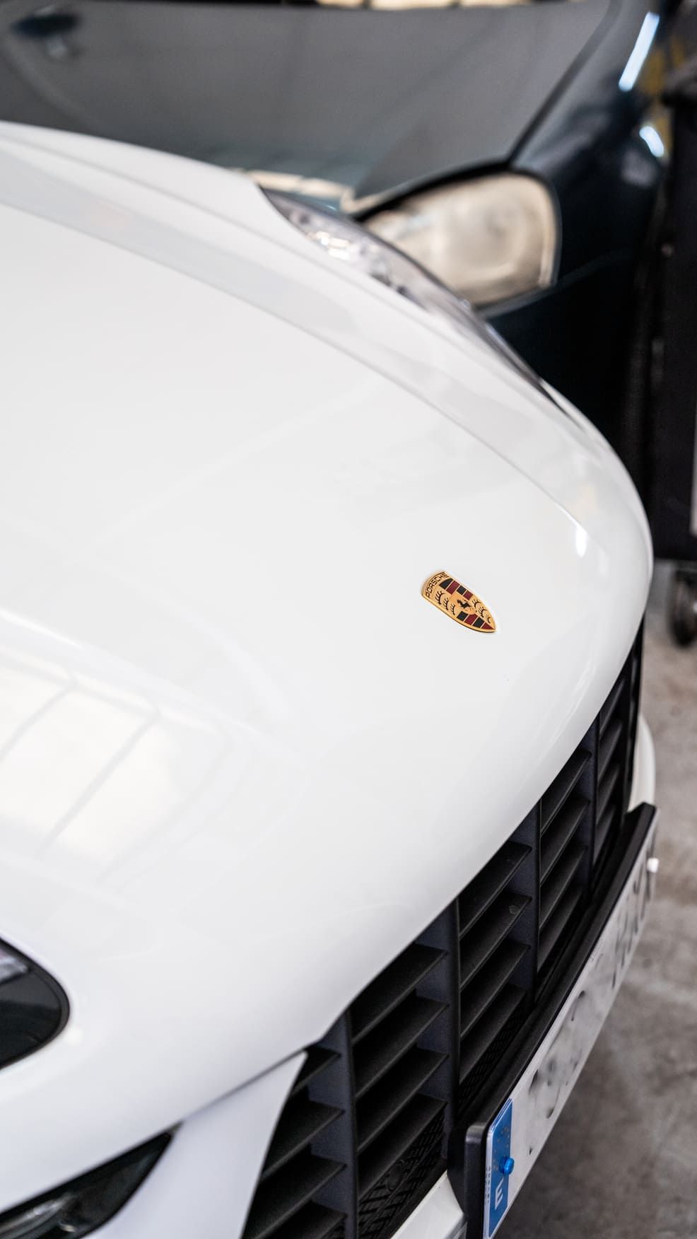 Un Porsche blanco está aparcado al lado de un coche negro.