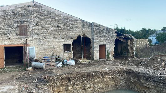 Mains et truelle appliquant un mortier gris entre des briques orange dans un mur