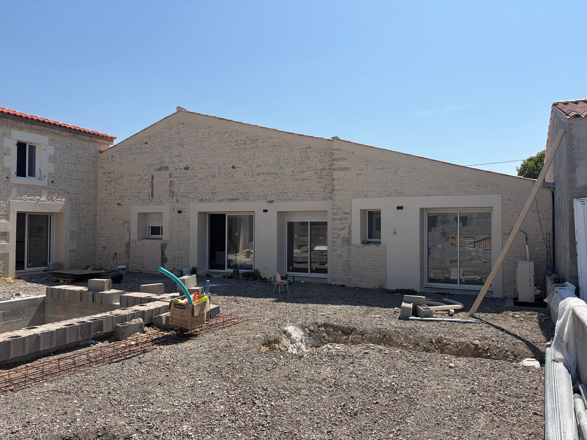Extérieur d'une maison neuve avec cour intérieure inachevée et matériaux de construction devant.