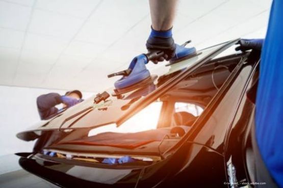 Zwei Personen legen eine Autoscheibe