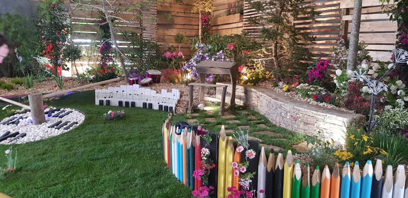Un jardin coloré avec une clôture en forme de crayons.