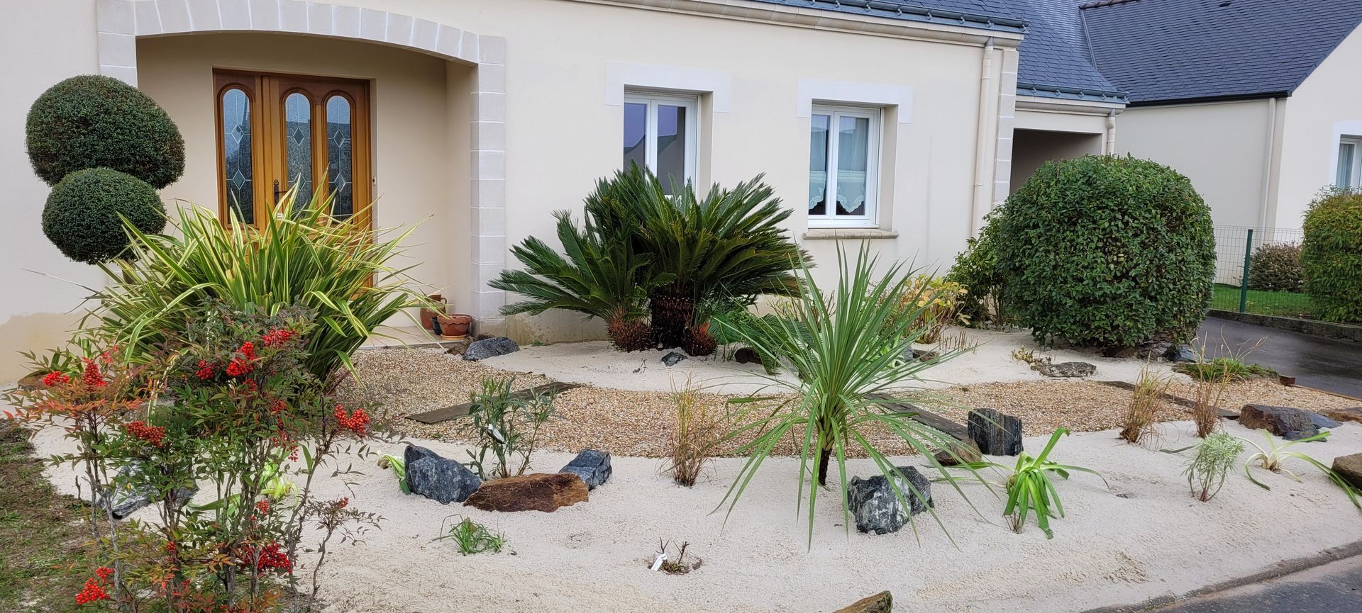 Un espace extérieur avec des plantes, des galets blancs et des pierres.
