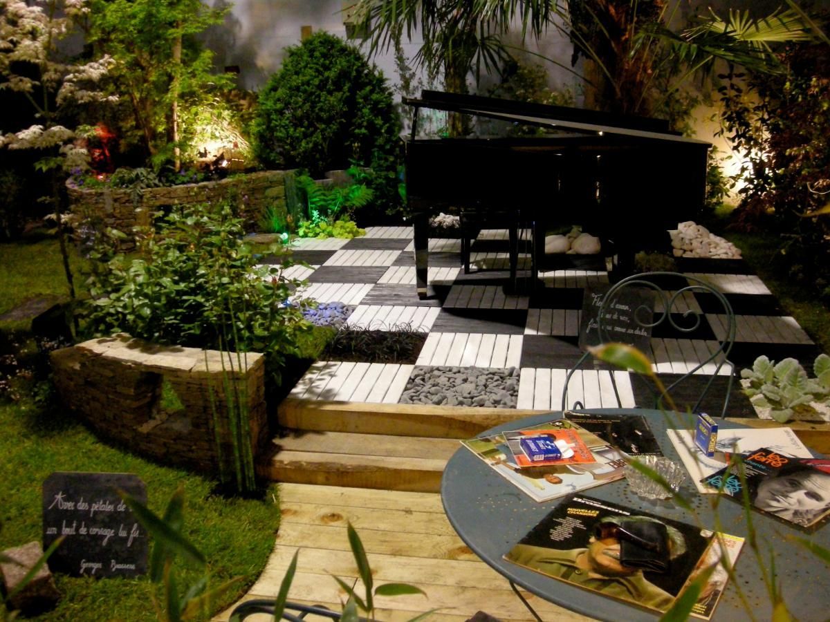 Un jardin avec un piano, une terrasse en damier noir et blanc.
