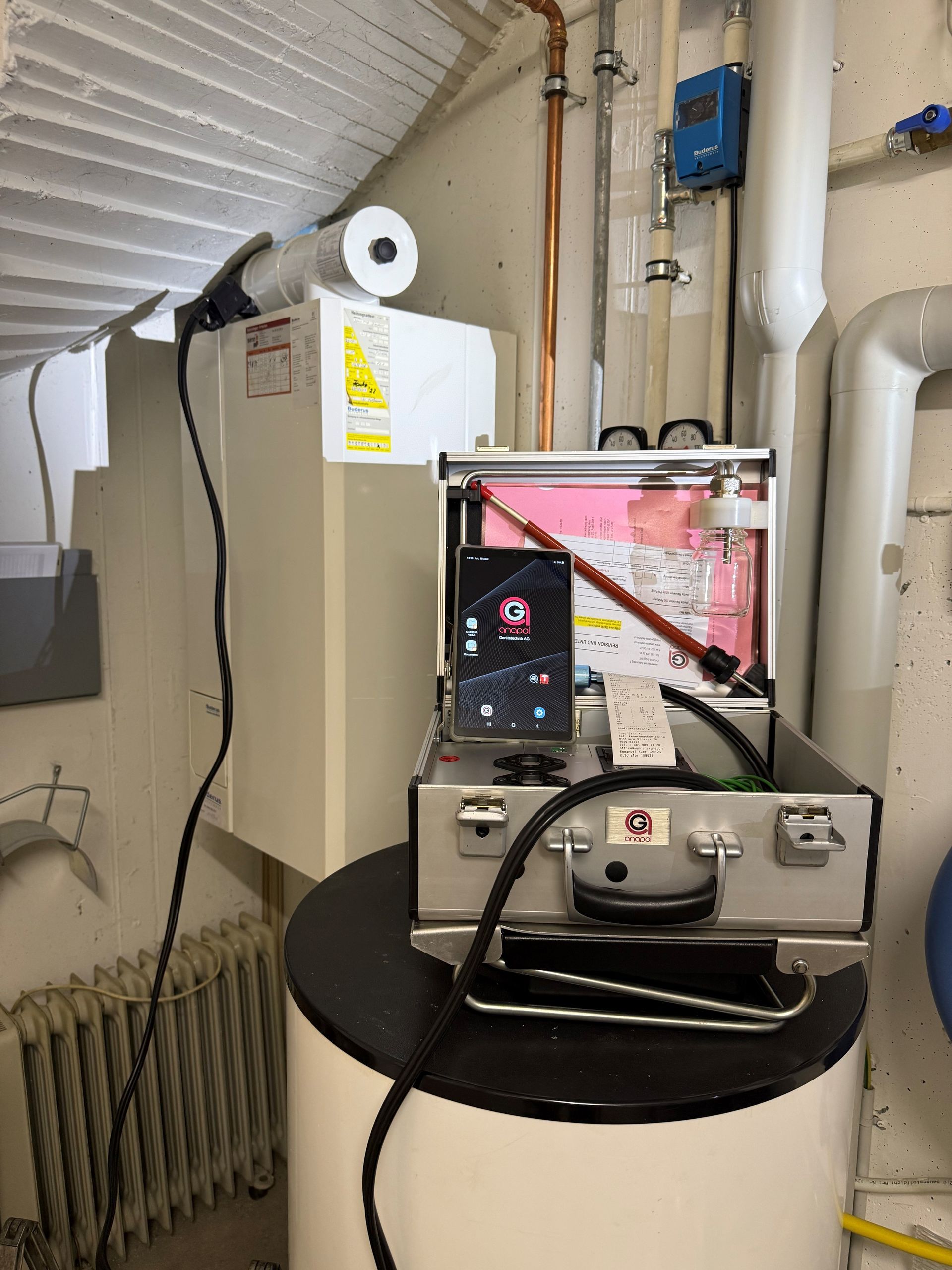 Eine Heizungsanlage wird mit einem mobilen Gerät und Equipment im Koffer überprüft.