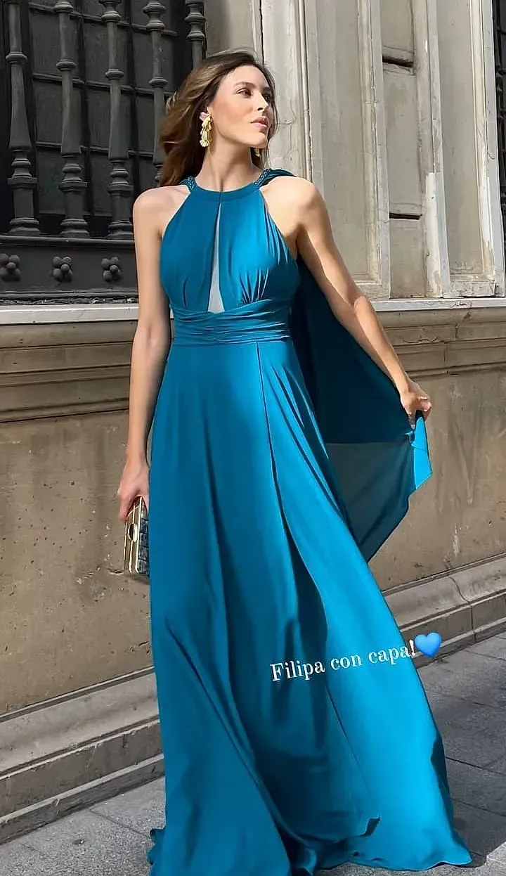 Una mujer con un vestido azul está parada frente a un edificio.