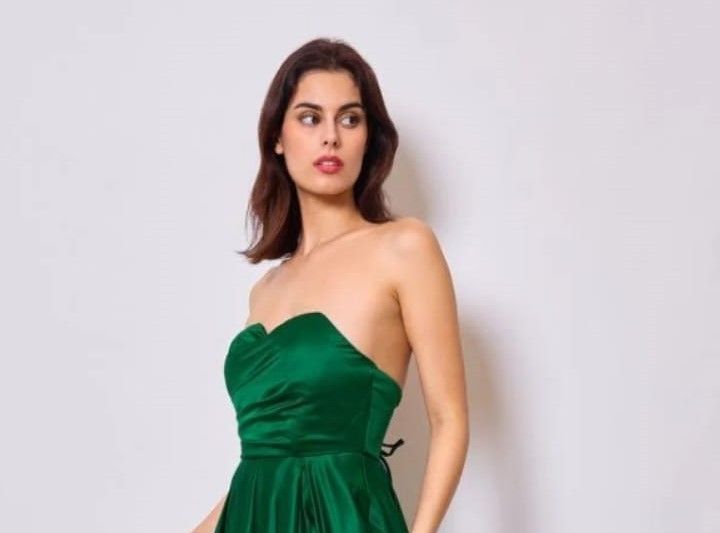 Una mujer lleva un vestido verde sin tirantes.