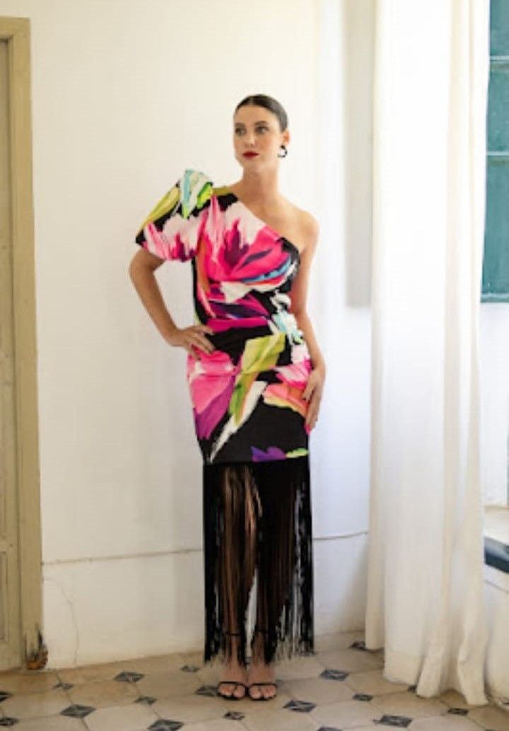 Una mujer con un vestido colorido está parada frente a una ventana.