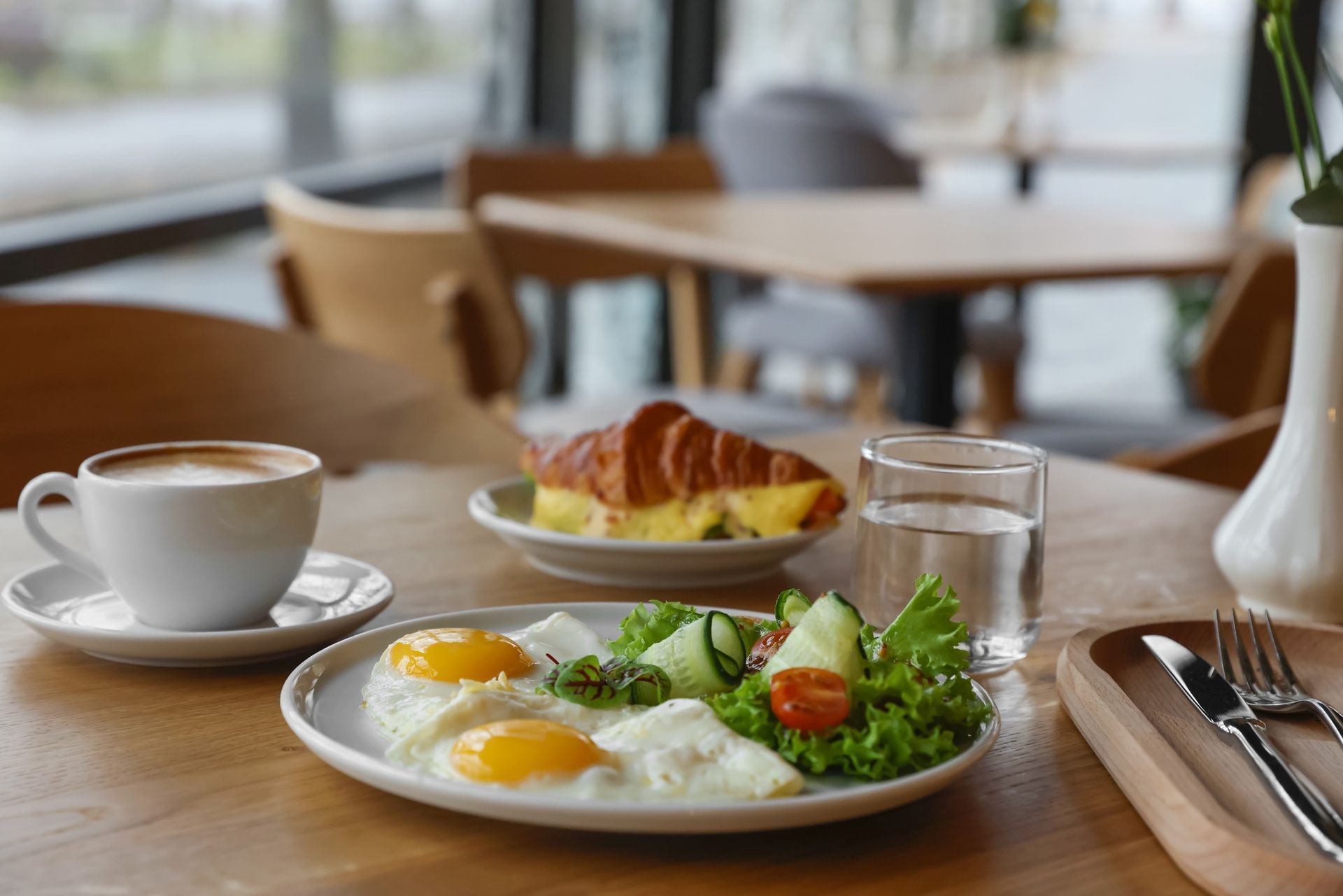 Hay un plato de huevos, un croissant y una taza de café en la mesa.