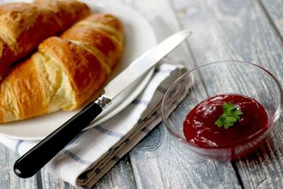 Hay un bol de mermelada al lado de un plato de croissants.