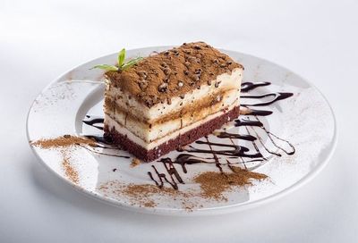 Un plato blanco cubierto con un trozo de pastel y salsa de chocolate.