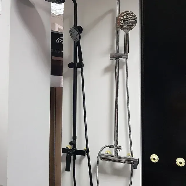 Un cabezal de ducha está colgado en una pared al lado de un cabezal de ducha.