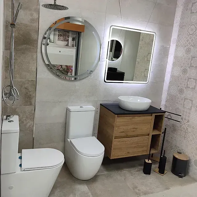 Un baño con inodoro, lavabo, espejo y ducha.