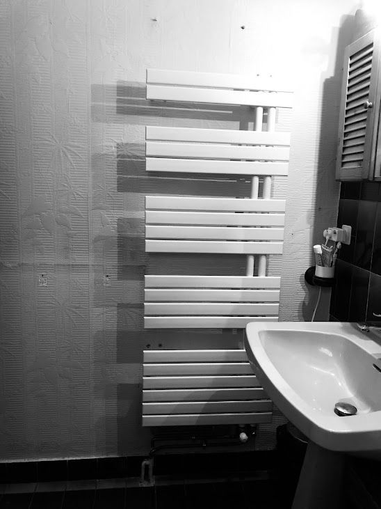 Sèche serviettes blanc dans une salle de bain grise blanche et noire