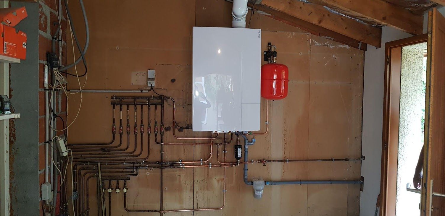 Tuyaux et chaudière blanche dans un petit espace