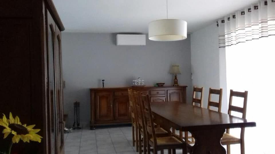 Salle à manger avec une grande table en bois possédant une climatisation