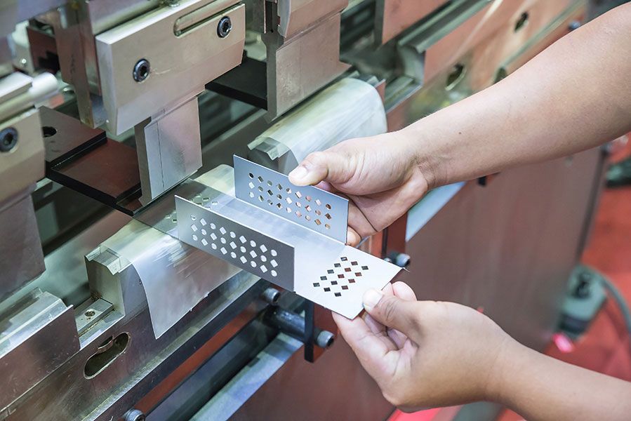 Una persona sostiene un trozo de metal delante de una máquina.