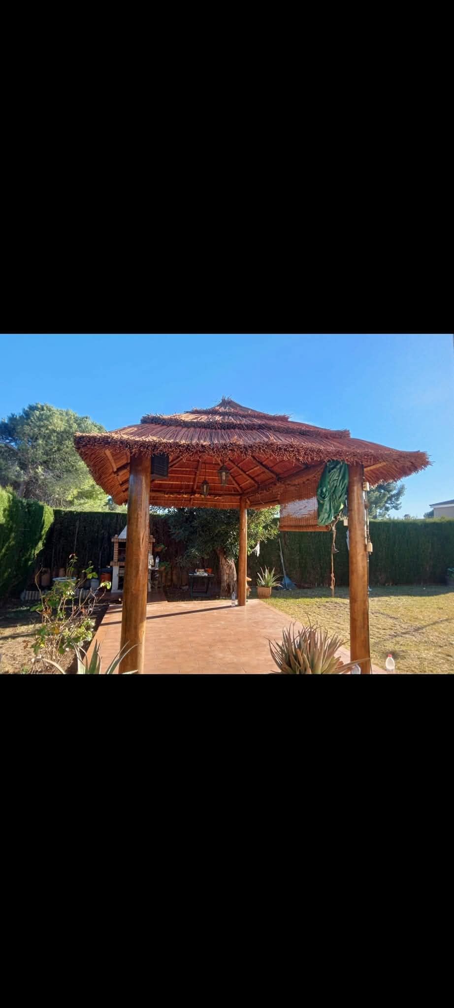 Un cenador de madera con techo de paja en un patio trasero.
