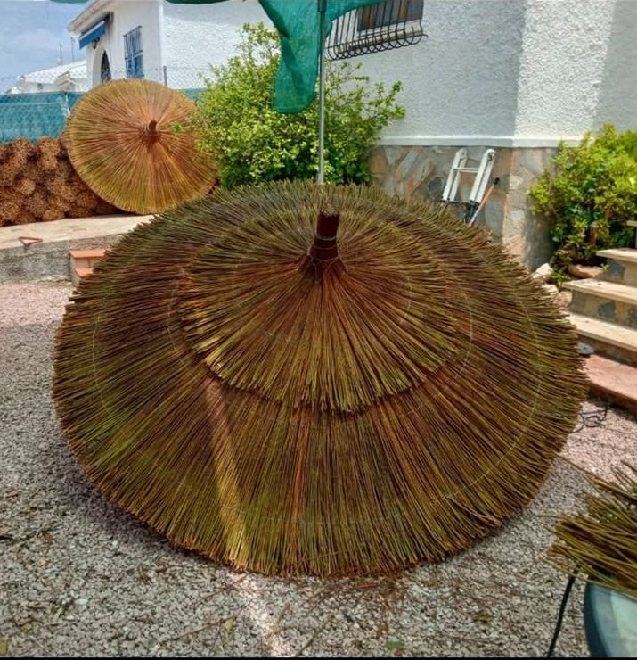 Una gran sombrilla de paja está delante de una casa.