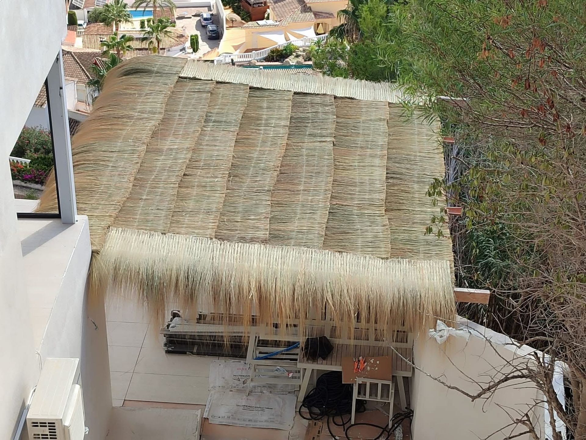 Un techo de paja se encuentra encima de un edificio blanco.