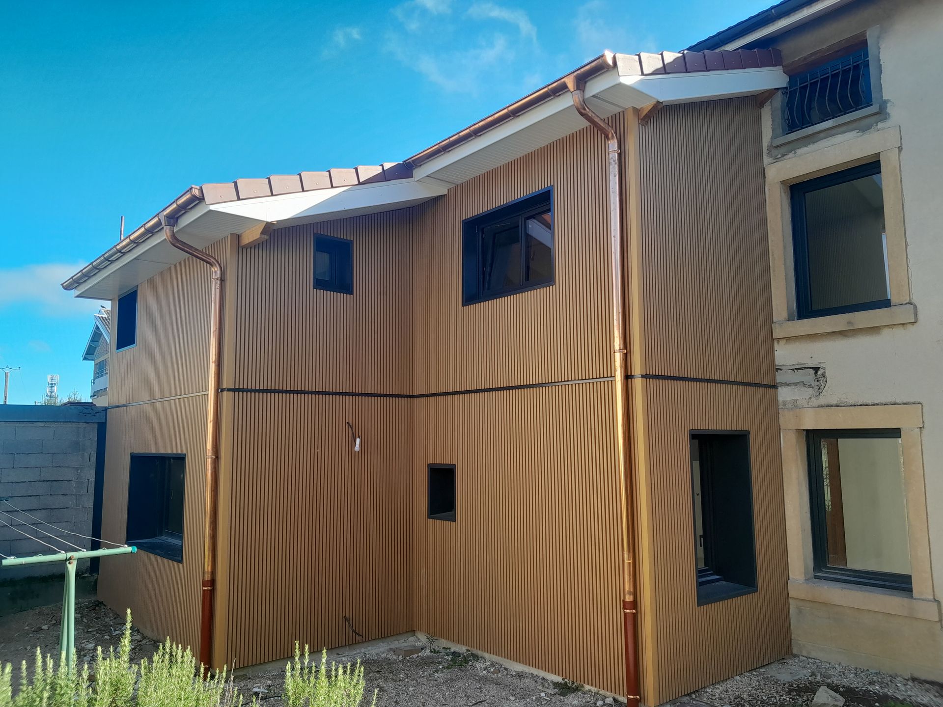 Extension à étage d'une maison avec des fenêtres et un bardage en bois.