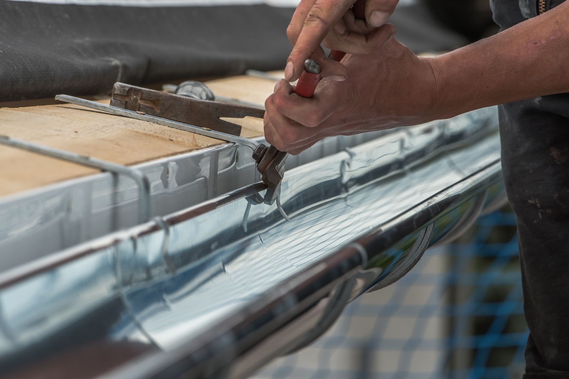 Un couvreur qui fixe une gouttière en zinc.