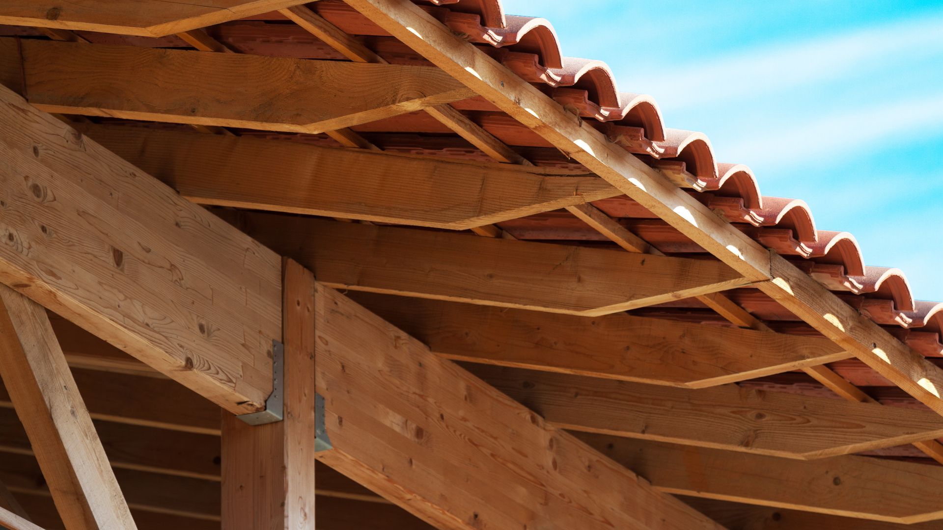 Toiture en bois avec avant-toit recouvert de tuiles en terre cuite et poutres apparentes.