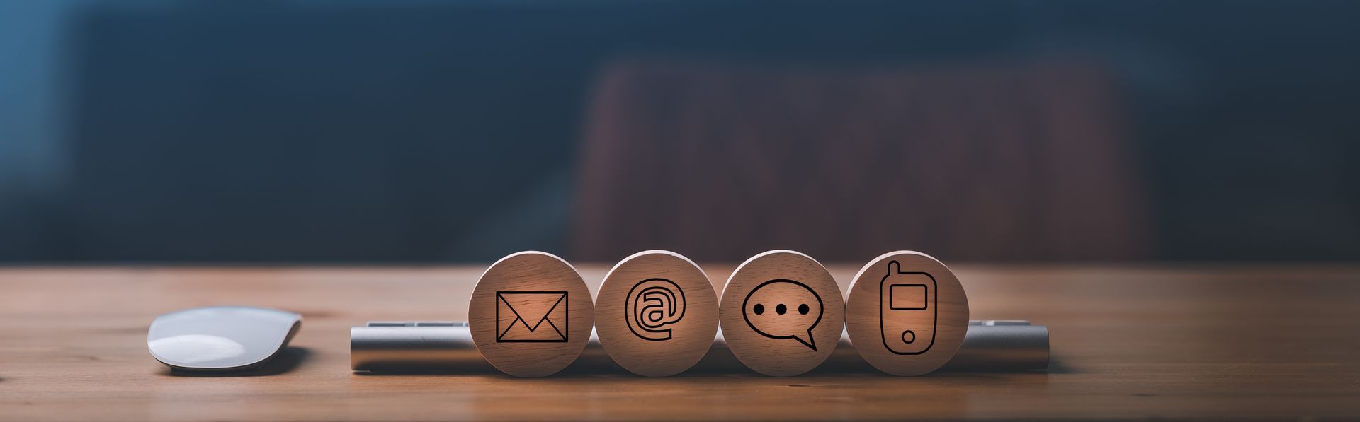 Quatre cercles en bois ornés d'une enveloppe, d'une arobase, d'une bulle de dialogue et d'un téléphone.
