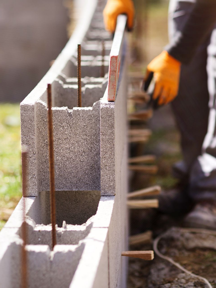 Un maçon qui construit un mur en parpaings.