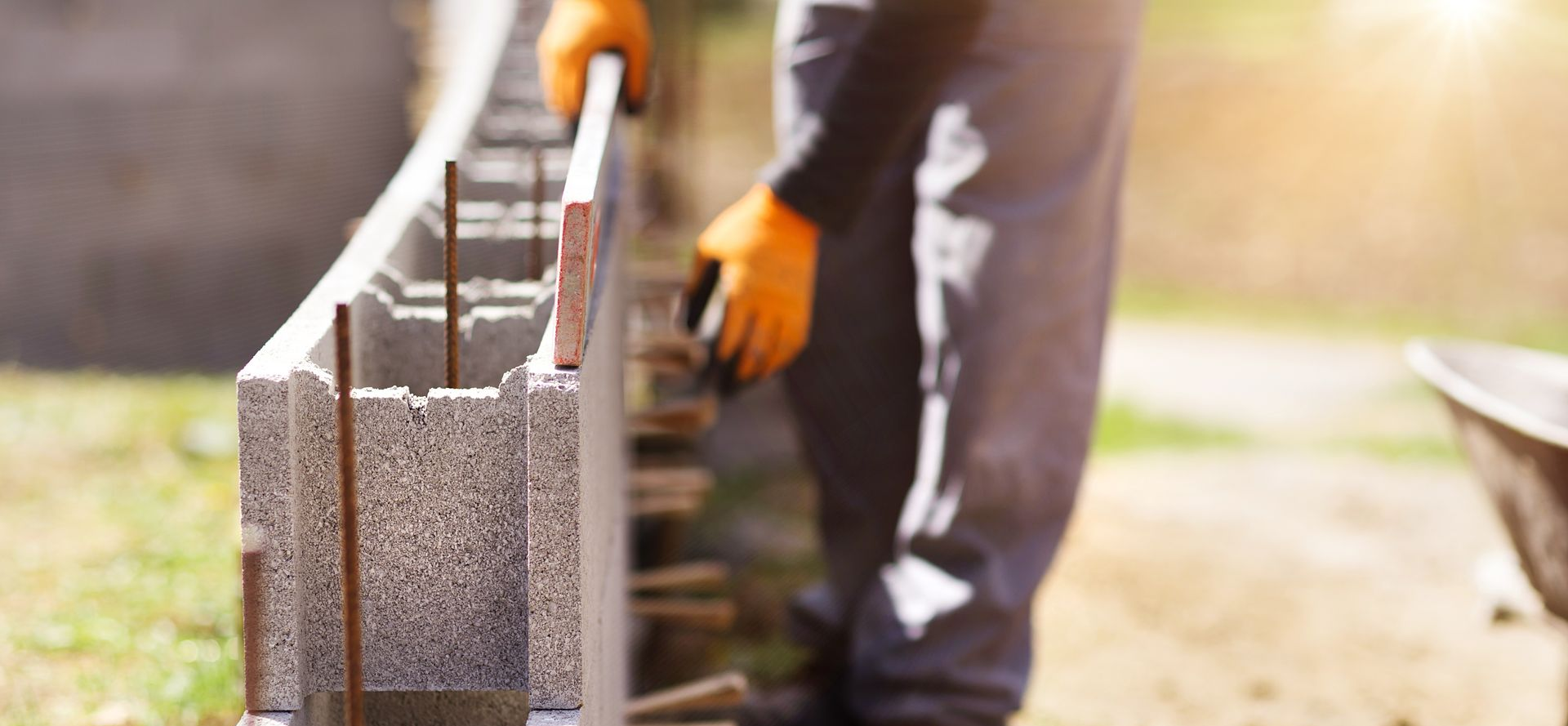 Un maçon qui mesure le niveau d'un mur de parpaings en construction.