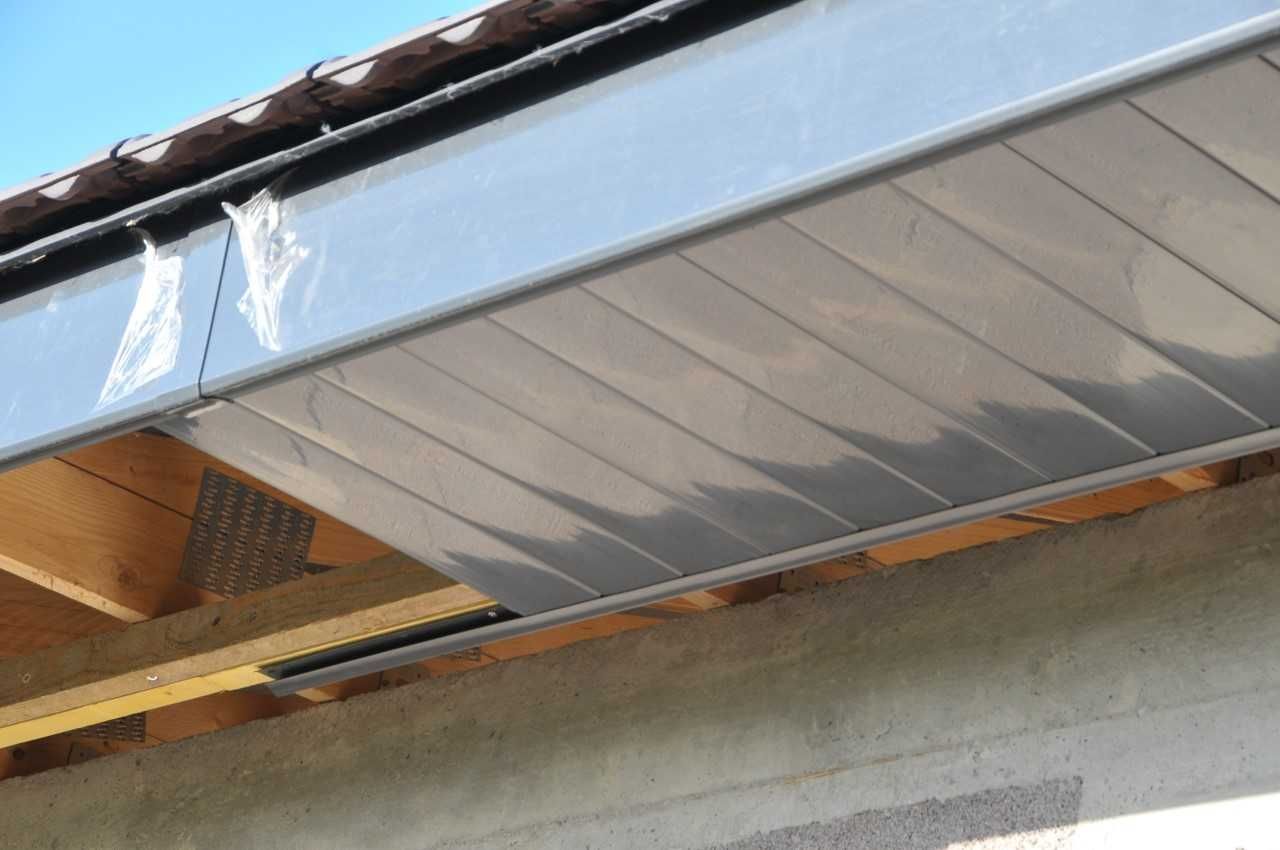 Sous-face grise à motif nervuré, installée sous le débord de toit.