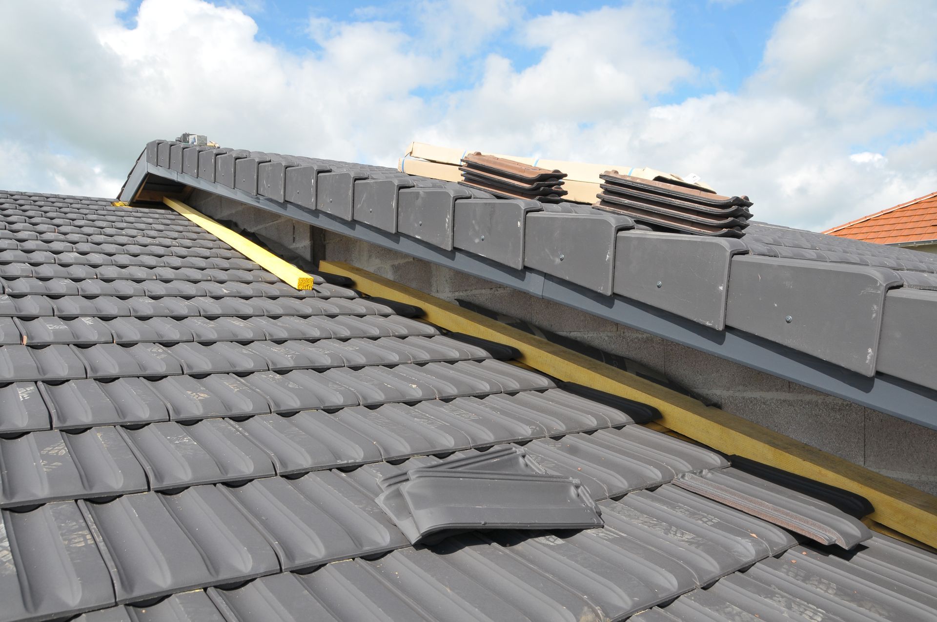 Toiture en tuiles orange en construction, laissant apparaître les supports en bois et la sous-couche en feutre.