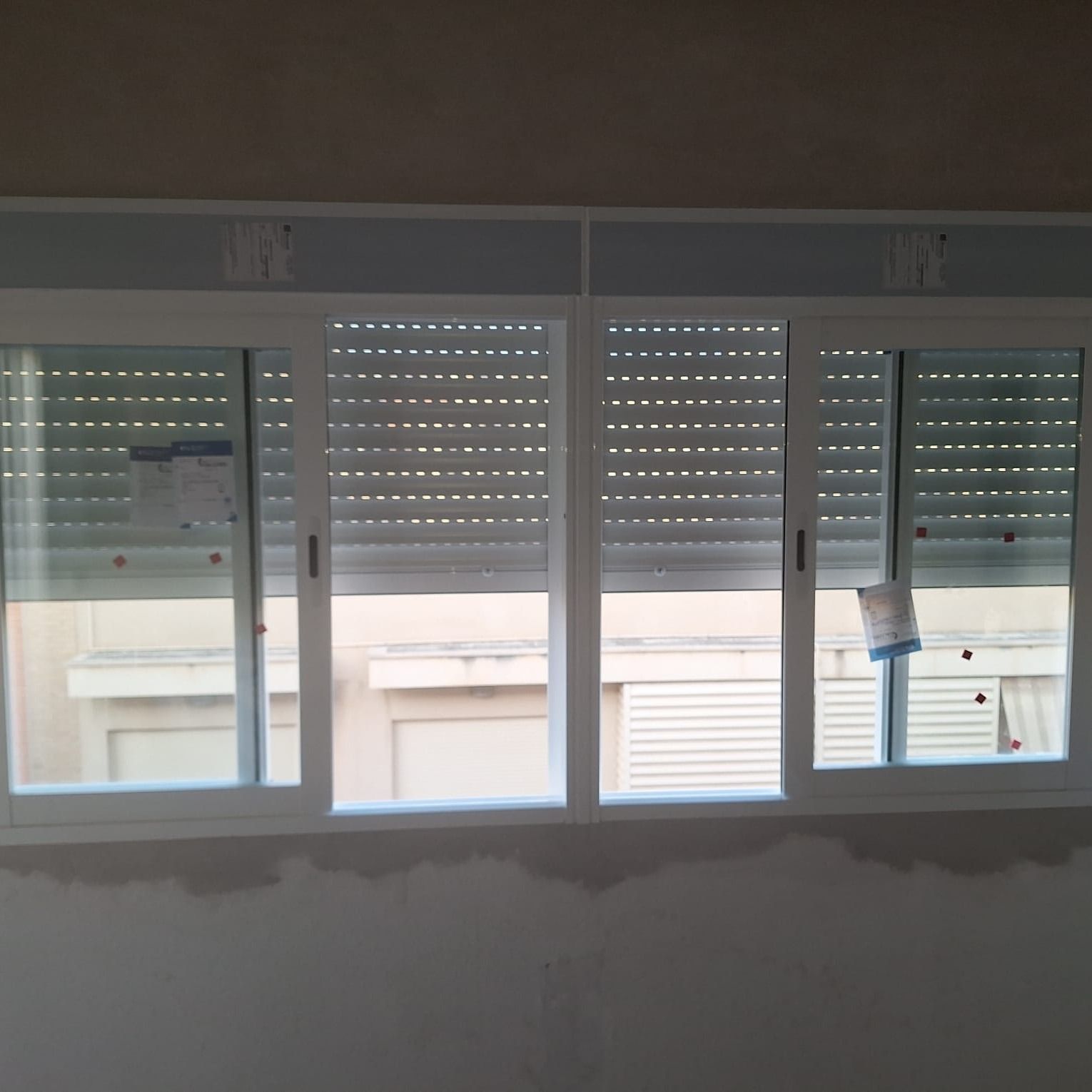 Ventana con marco blanco y persianas cerradas.