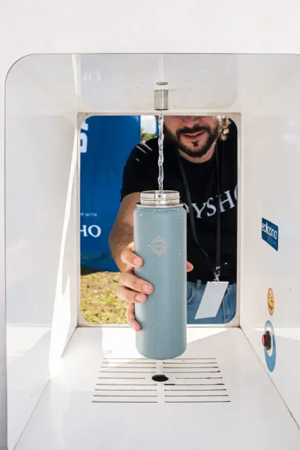 Cabina telefónica pública verde en un parque arbolado con letreros que dicen