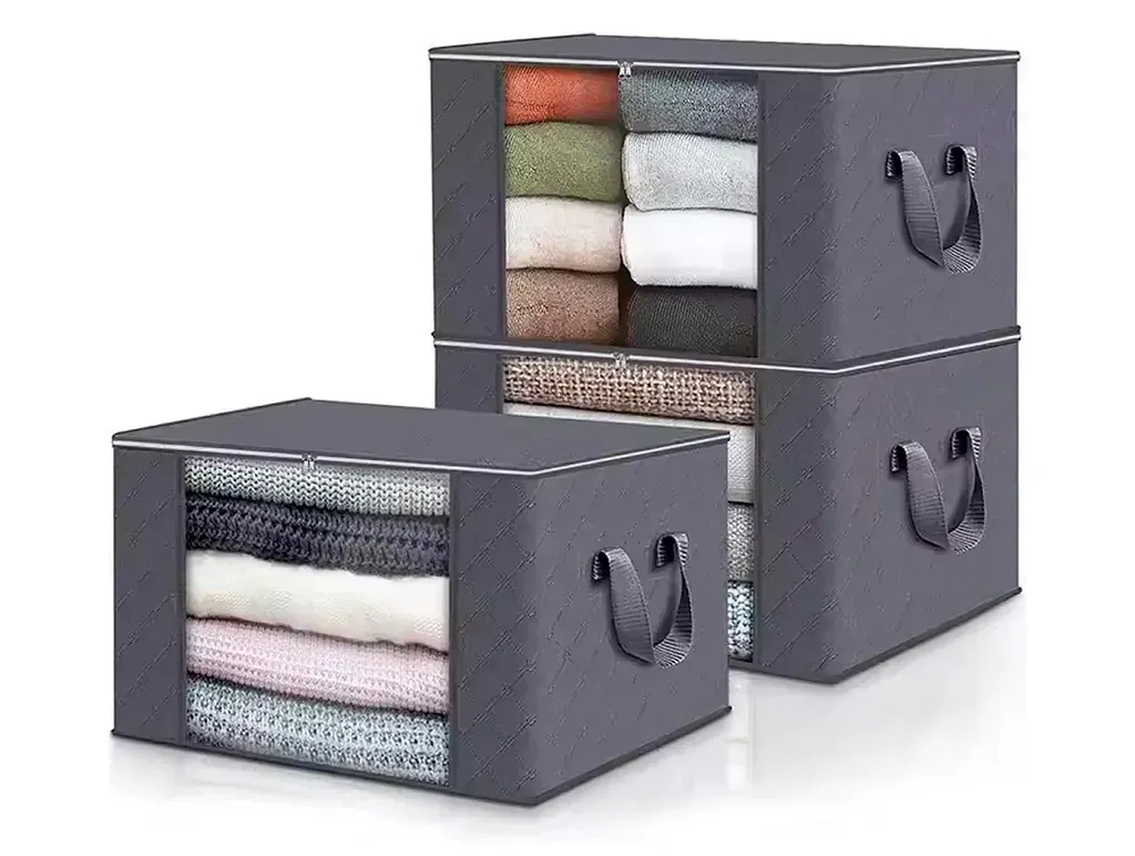Cajas de almacenamiento de tela gris con ventanas transparentes, apiladas con ropa doblada.