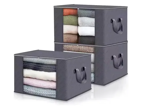 Cajas de almacenamiento de tela gris con ventanas transparentes, apiladas con ropa doblada.