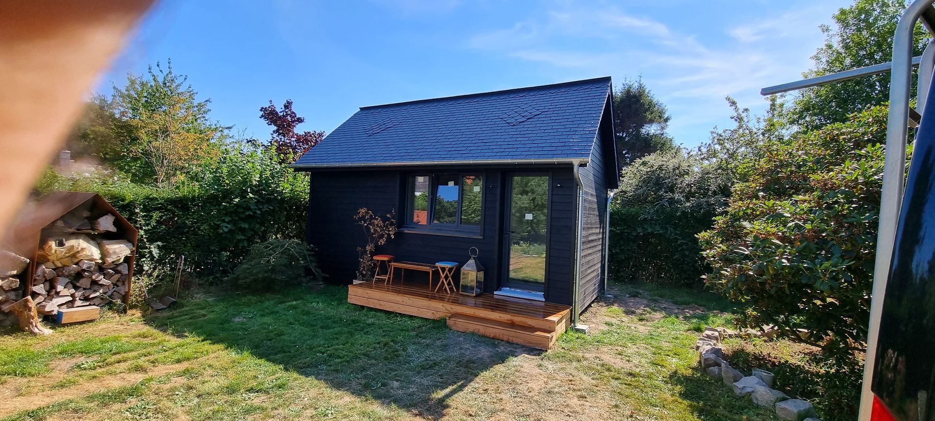 Petite maison noire en bois dans un jardin