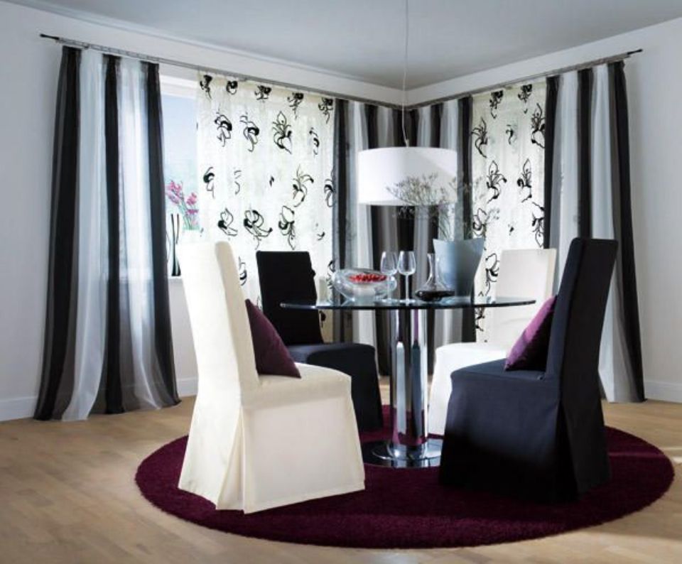 Esszimmer mit Tisch und Stühlen und gestreiften und gemusterten Gardinen